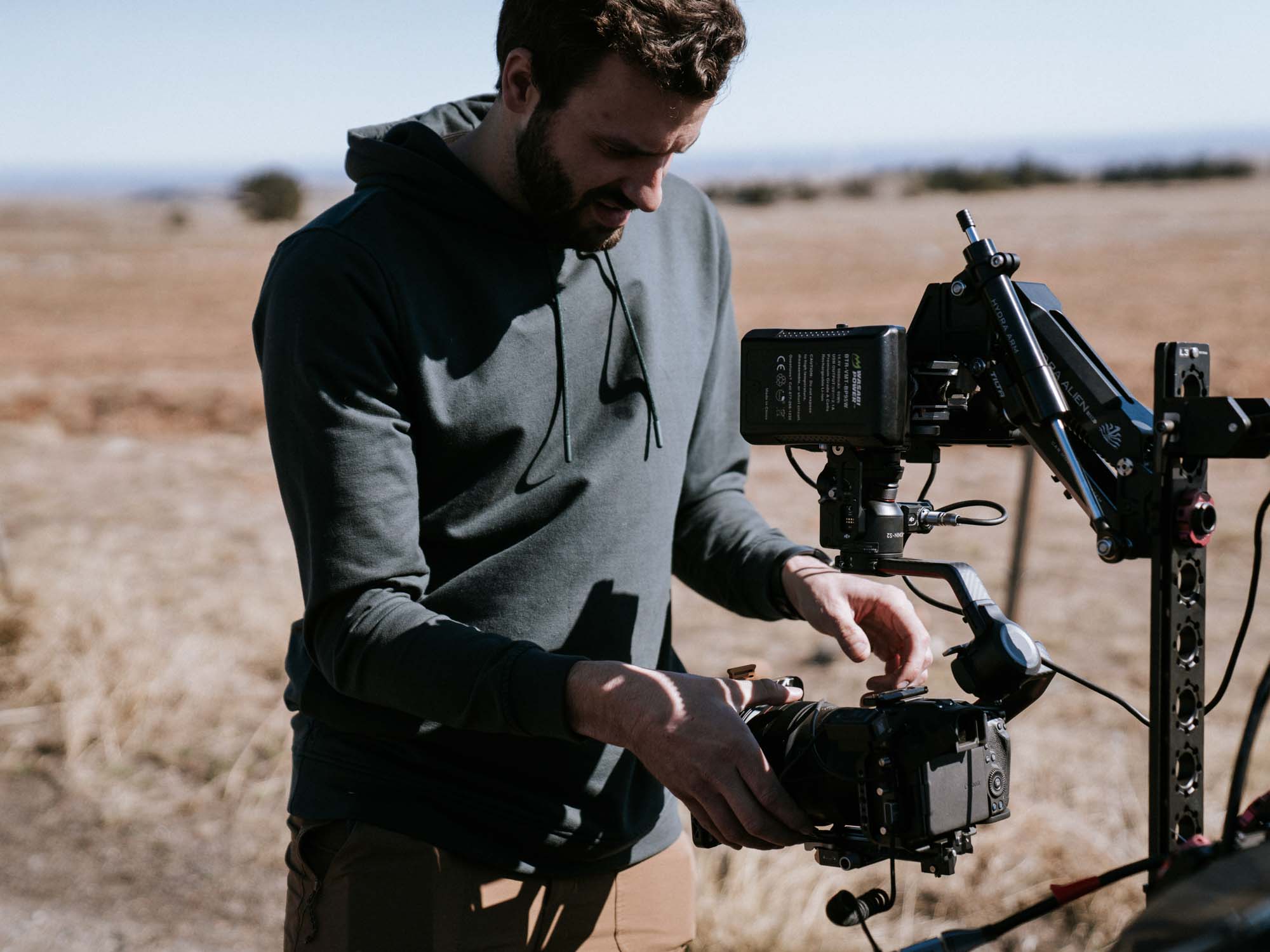 videographer setting up cinema camera rig outdoors for commercial video production shoot